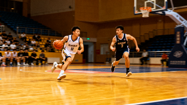 室内篮球比赛现场，球员在球场上进行进攻配合